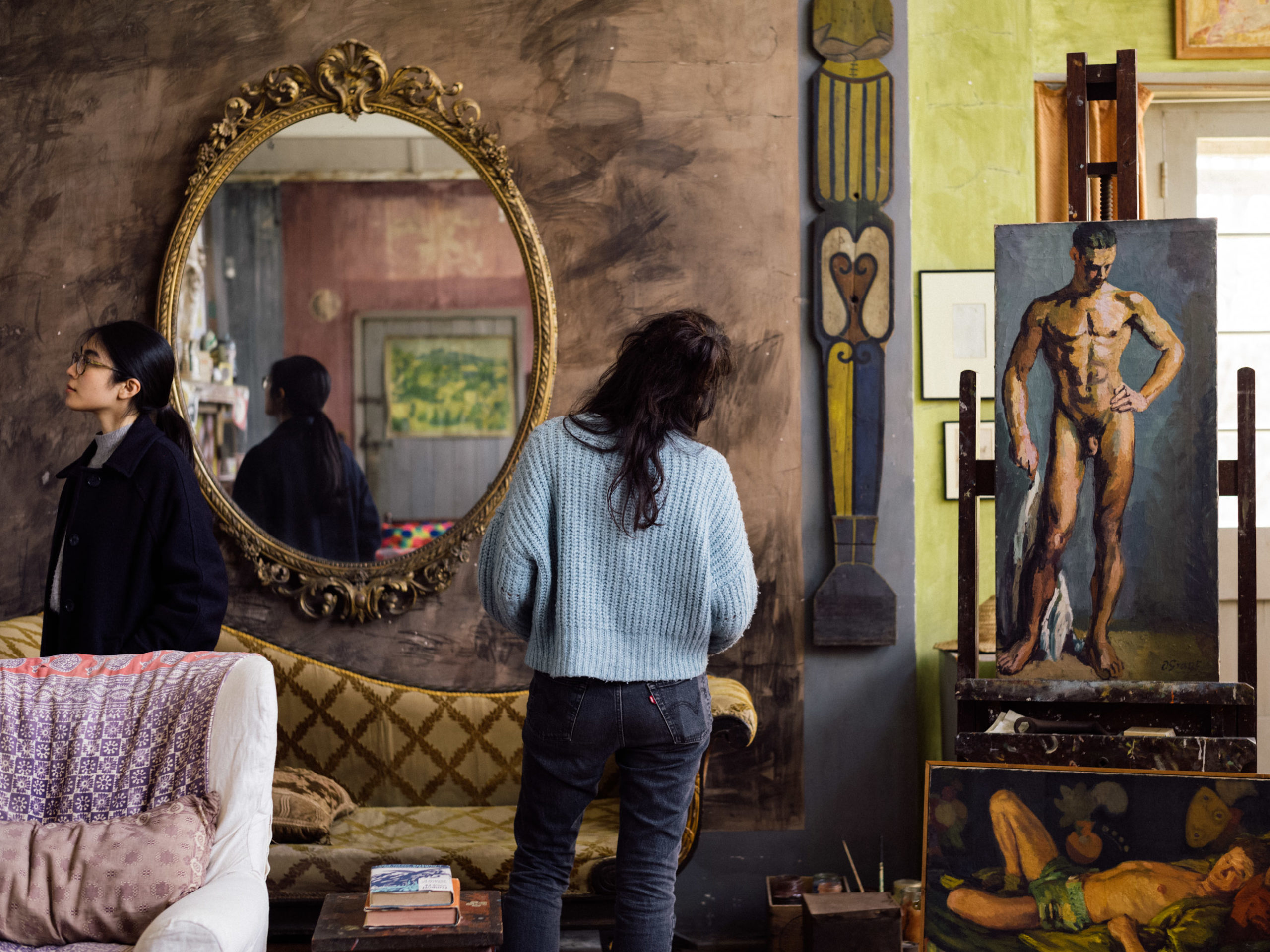 A photograph of two visitors in the studio at Charleston. One visitor is reflected in the mirror